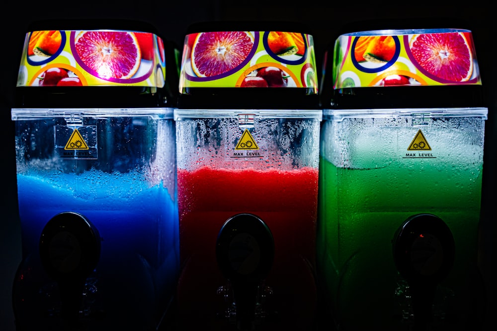 three soda machines with different colors of liquid