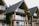 A series of modern wooden houses with large glass windows and triangular, black shingled roofs. The architecture features balconies with glass railings, creating a sleek and contemporary appearance.