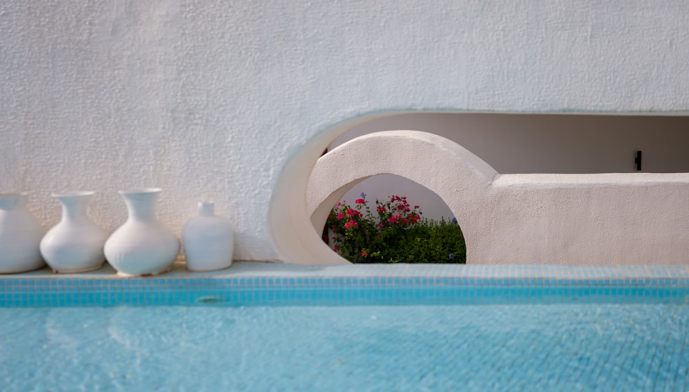 a row of vases sitting next to a swimming pool