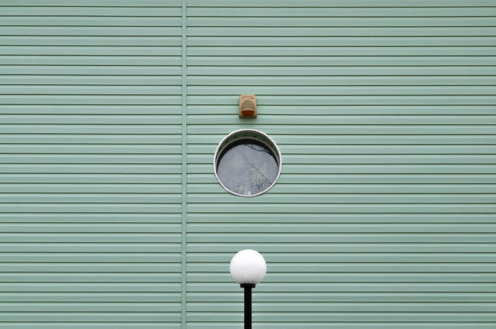 a street light next to a green wall