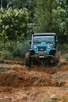 A muddy side-by-side tearing through a forest trail, splashing mud and leaves.