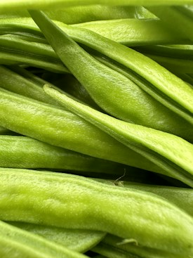A close-up view of fresh, green beans with a smooth texture and vibrant color, filling the entire frame.