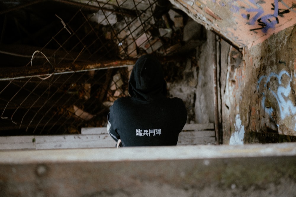 a person in a black hoodie sitting on a bench