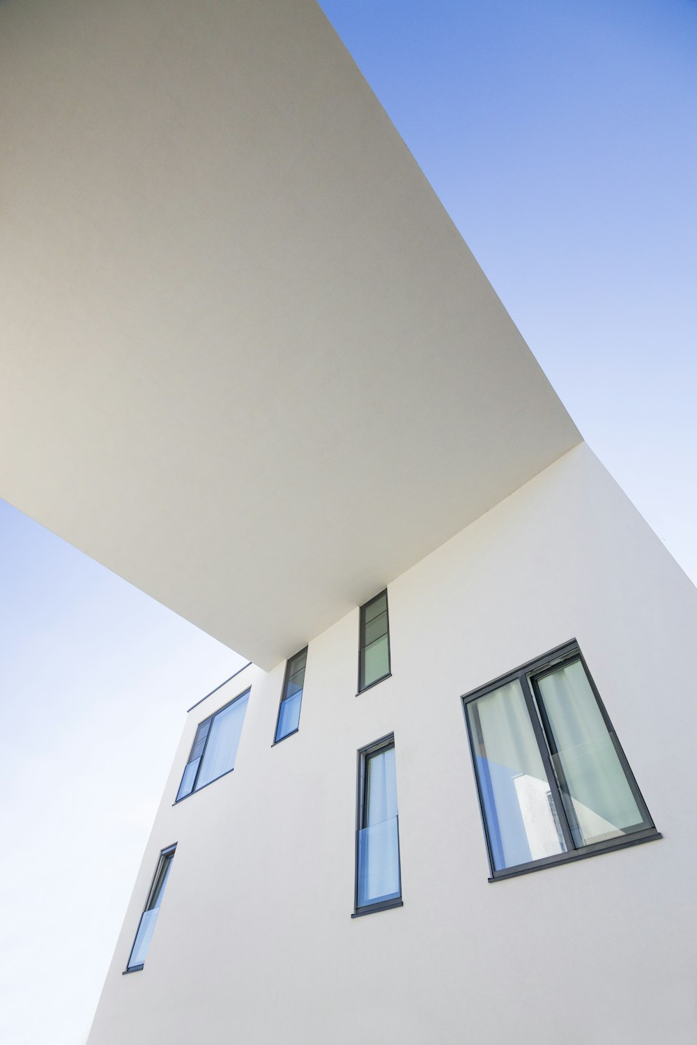 a tall white building with windows and a sky background