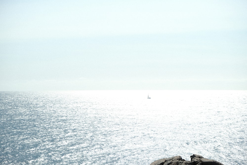 a lone sailboat in the distance on the ocean