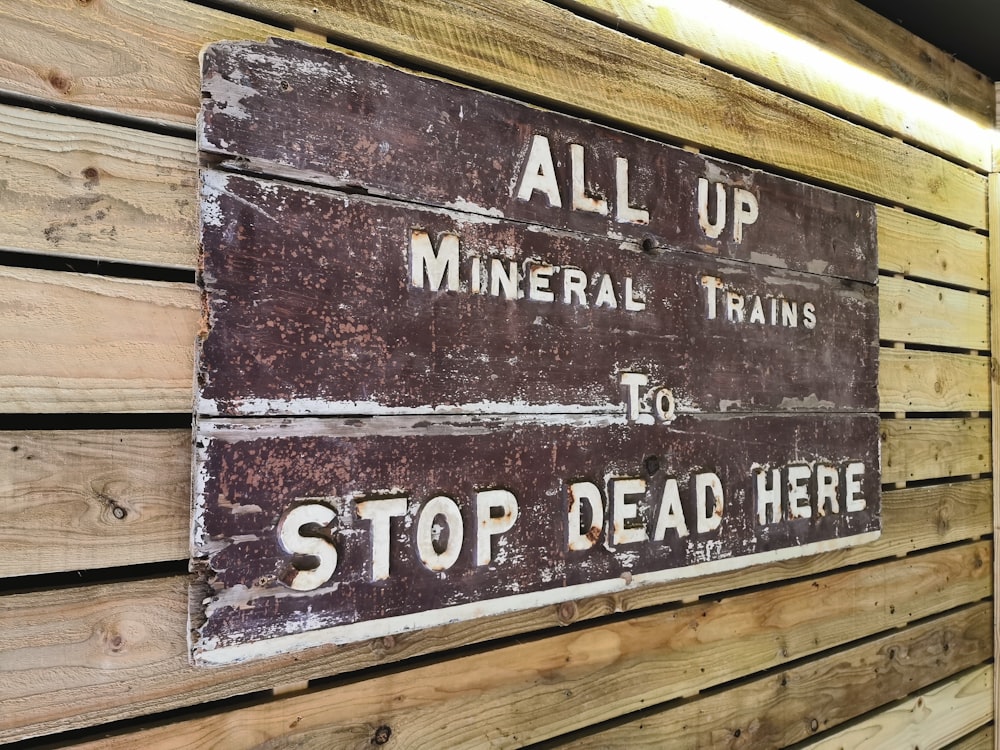 a sign on a wooden wall that says all up mineral trains to stop dead here