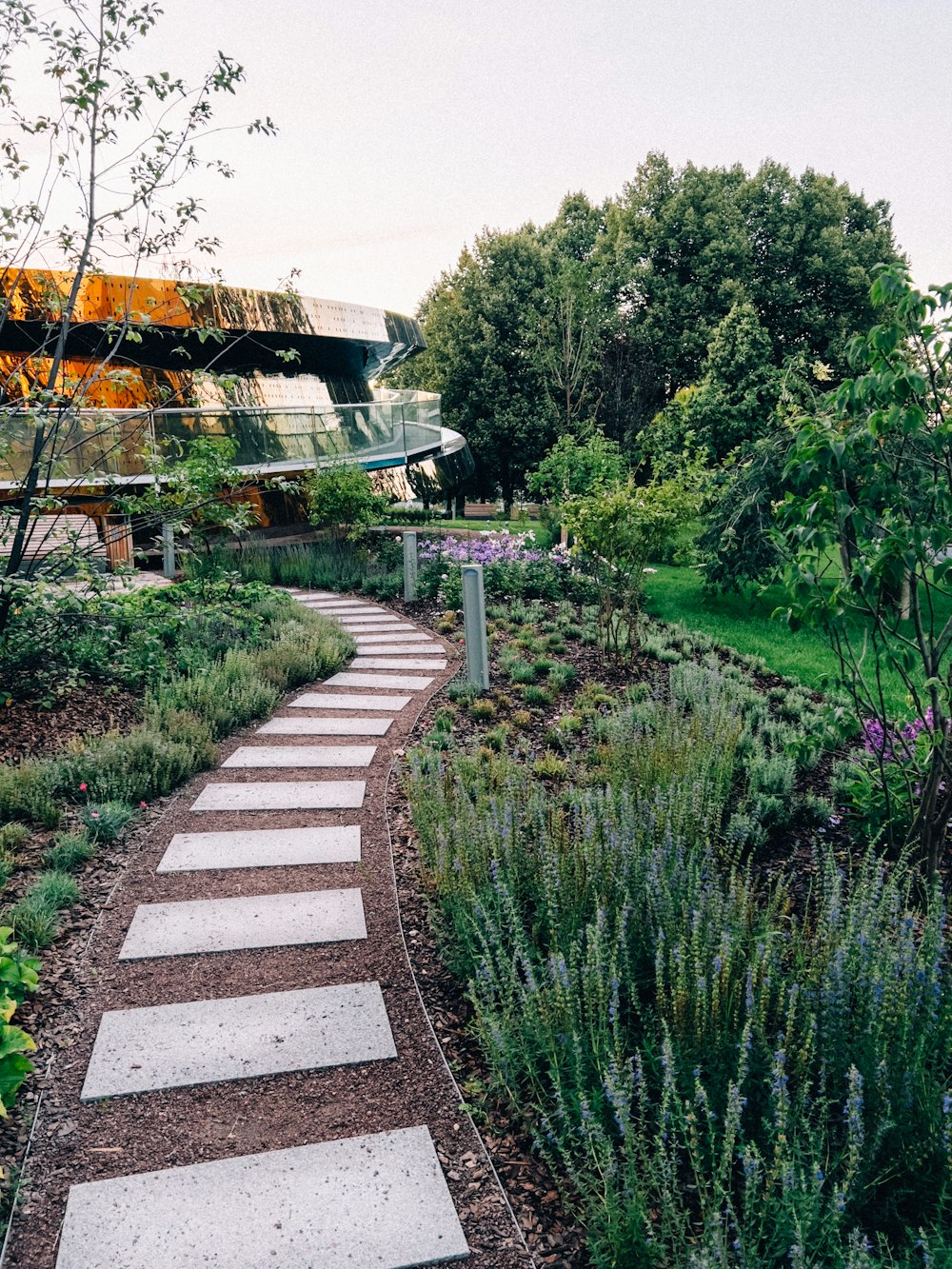 ein Gehweg in einem Garten mit einem Gebäude im Hintergrund