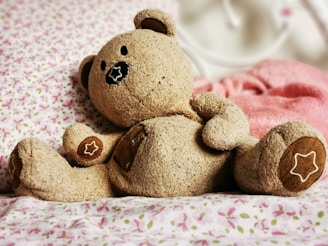 A friendly brown teddy bear sitting with colorful animated stars around it.