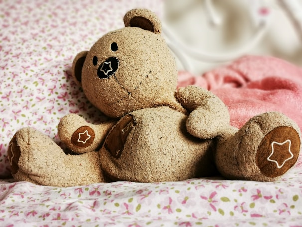A friendly brown teddy bear sitting with colorful animated stars around it.