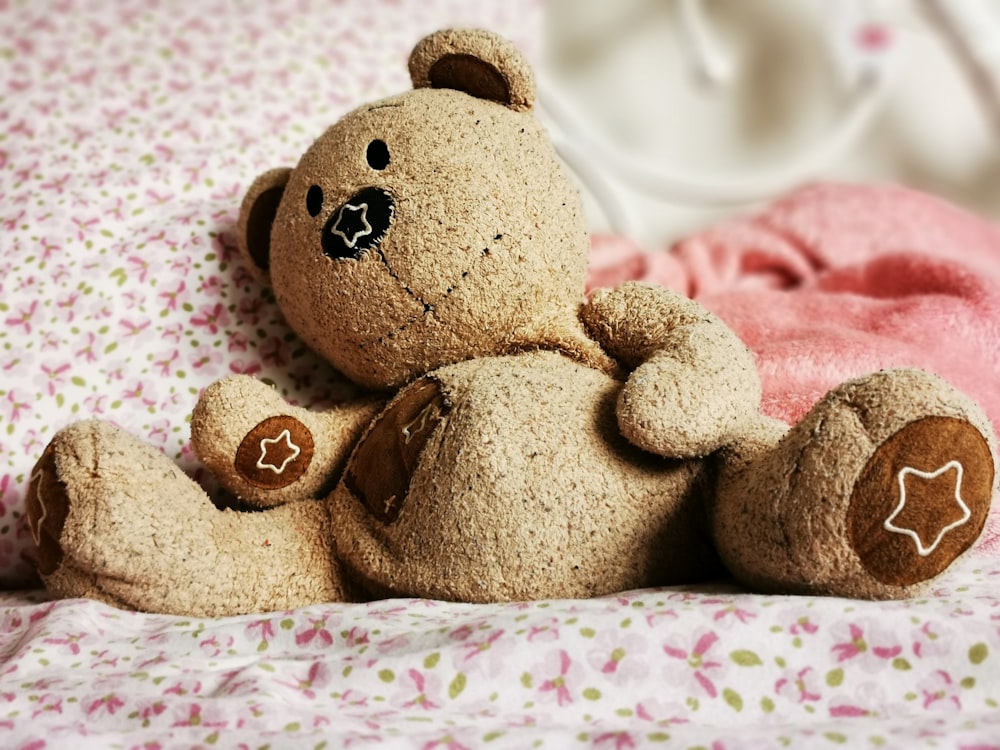 a brown teddy bear sitting on top of a bed