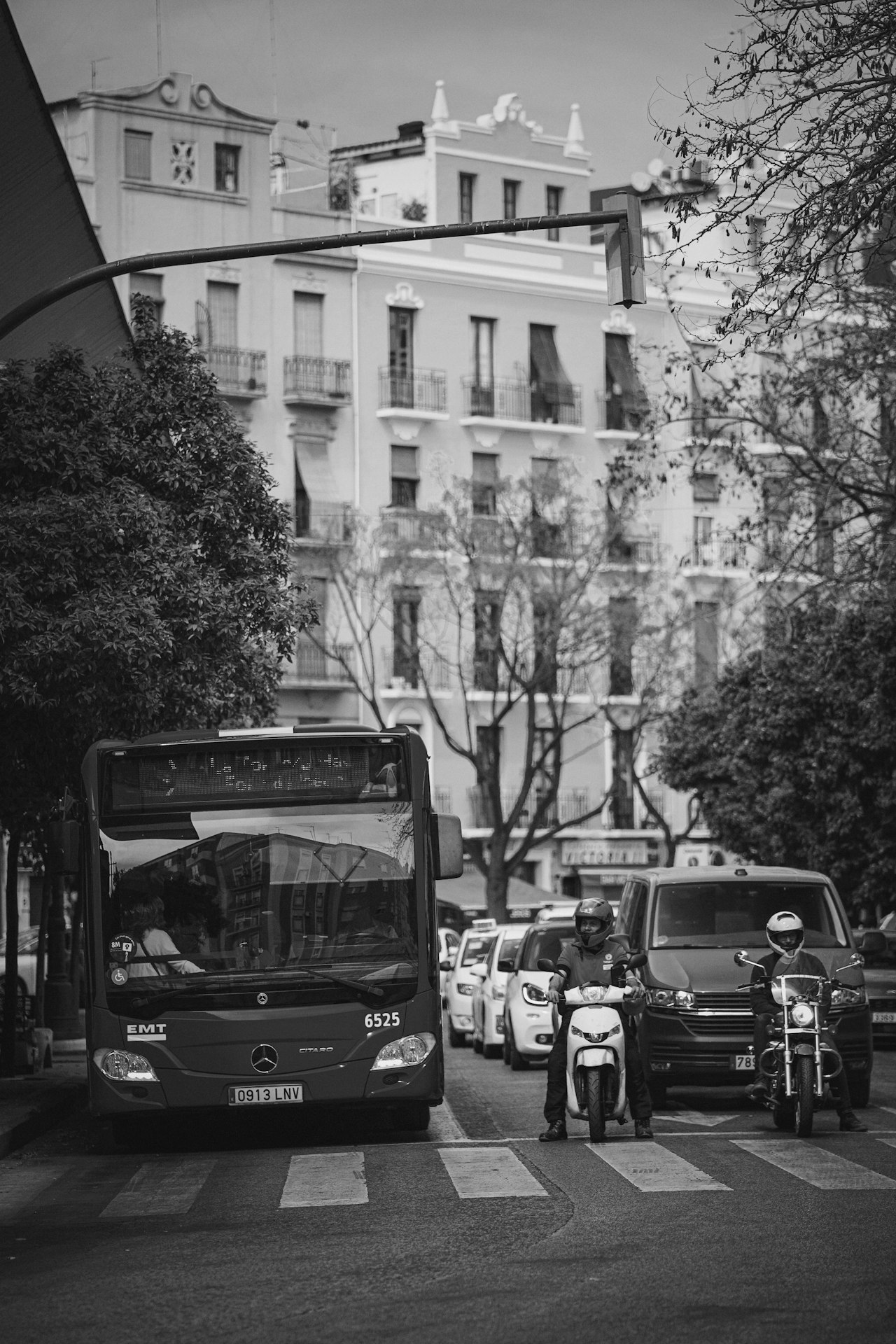 Valencia red bus driving down a street next to tall buildings