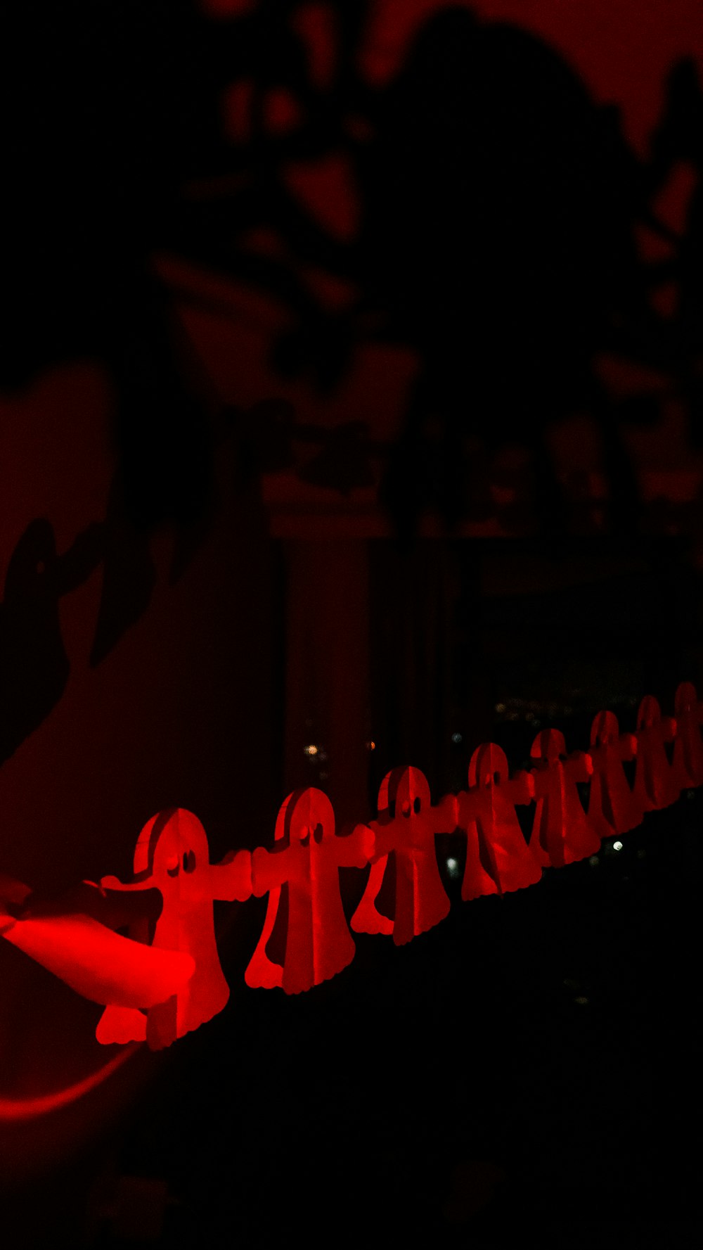 a long line of red paper figures in the dark