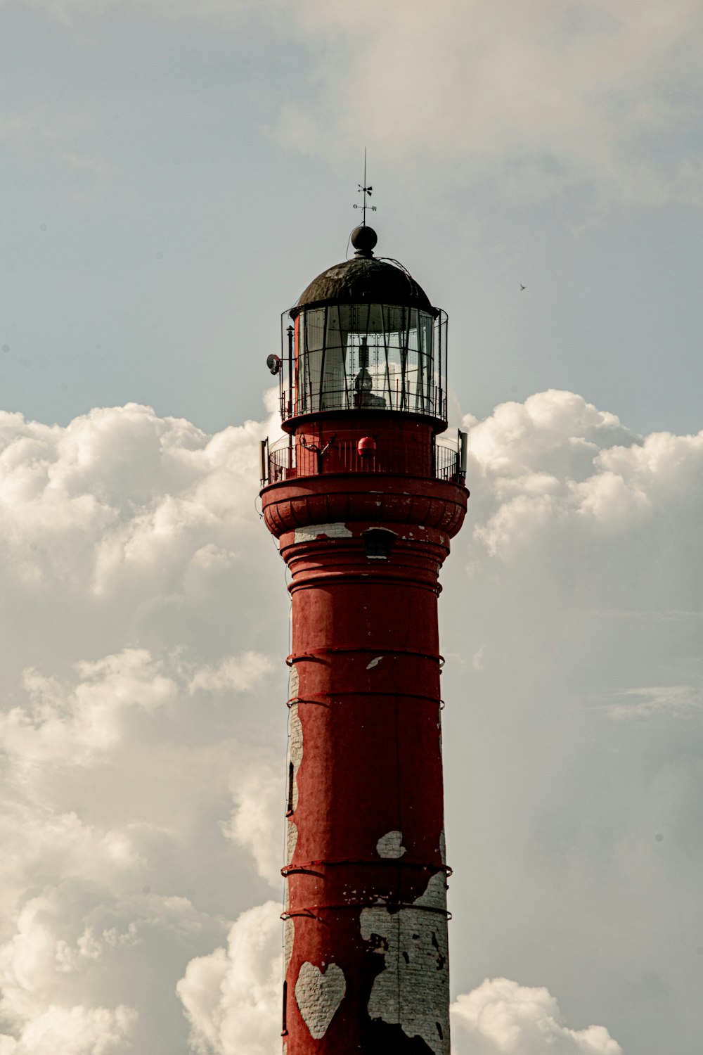 a red light house in the middle of a cloudy sky