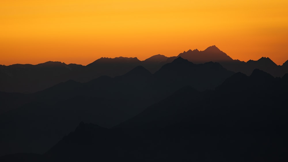 the sun is setting over a mountain range