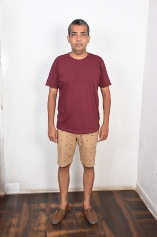 Model wearing a navy marell polo shirt standing against a minimalist white wall, showcasing the perfect fit.