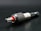 A close-up view of a metallic drill bit adapter featuring a textured, knurled grip and a visible red accent. The tool is placed on a dark surface, highlighting its polished metal components.