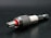 A close-up view of a metallic drill bit adapter featuring a textured, knurled grip and a visible red accent. The tool is placed on a dark surface, highlighting its polished metal components.