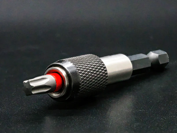 Close-up of a rugged cordless drill with metallic accents resting on a worn workbench.