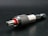A close-up view of a metallic drill bit adapter featuring a textured, knurled grip and a visible red accent. The tool is placed on a dark surface, highlighting its polished metal components.