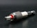 A close-up view of a metallic drill bit adapter featuring a textured, knurled grip and a visible red accent. The tool is placed on a dark surface, highlighting its polished metal components.