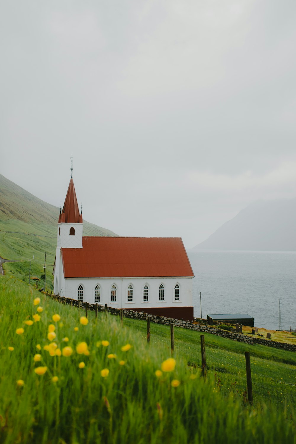 a white church with a red roof on a hill