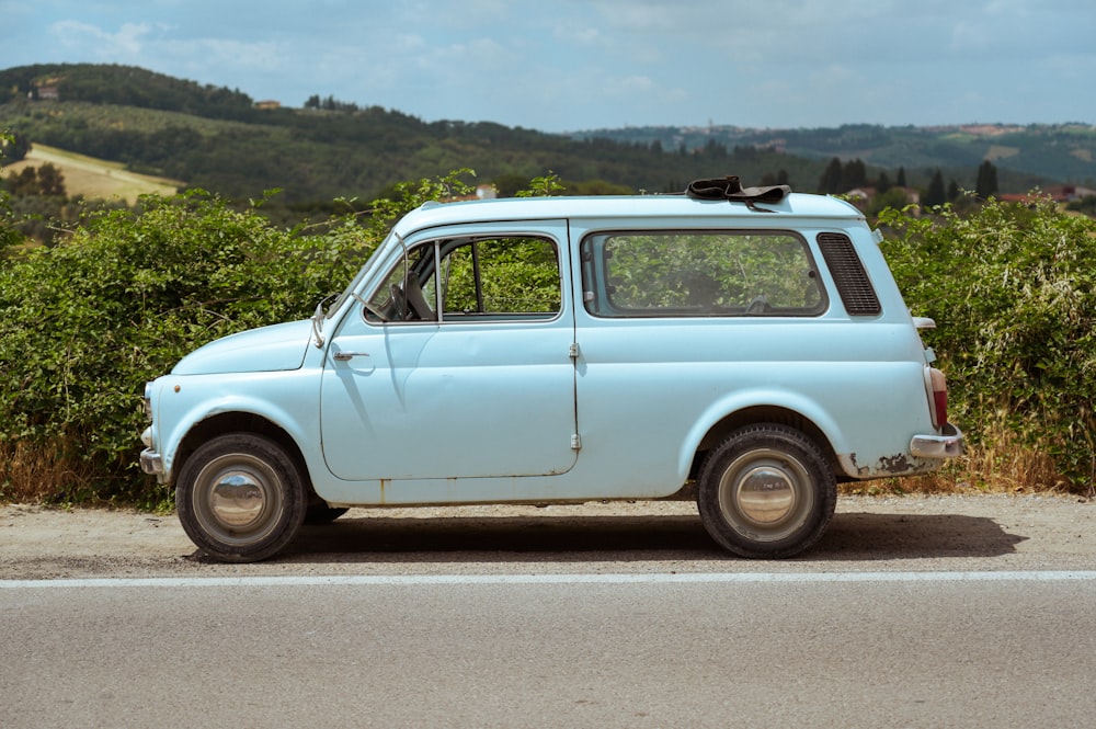 an old blue car parked on the side of the road