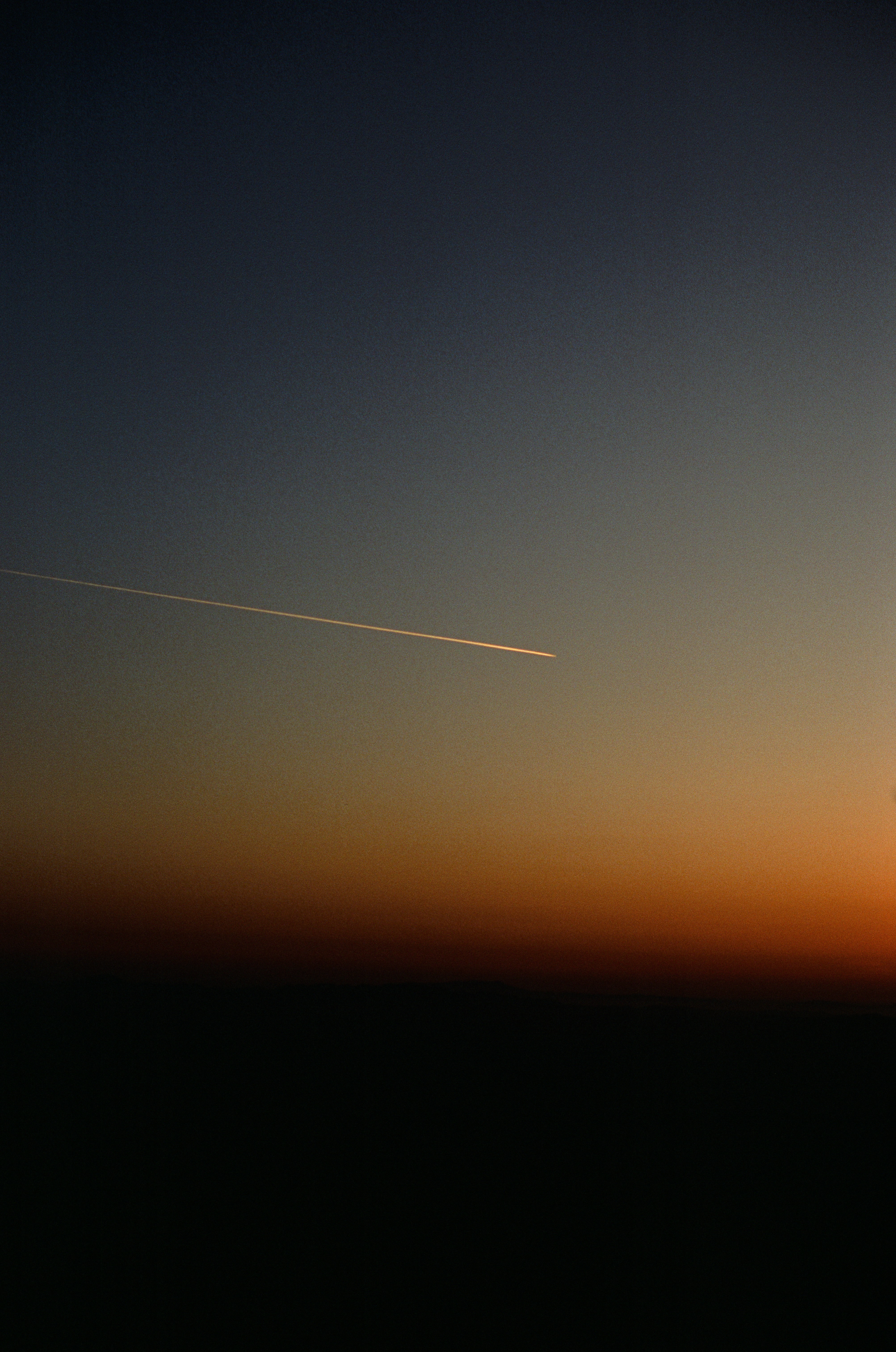 a plane flying in the sky at sunset