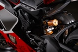 Close-up view of a motorcycle's rear section, highlighting the suspension system and chassis components. The metallic and vibrant finish, along with the intricate mechanical details, suggest high-performance engineering.