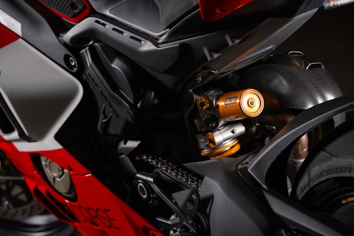 Close-up view of a motorcycle's rear section, highlighting the suspension system and chassis components. The metallic and vibrant finish, along with the intricate mechanical details, suggest high-performance engineering.