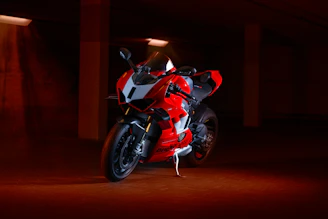 A sleek, black and red sport motorcycle showcased under dramatic lighting on a dark urban street.