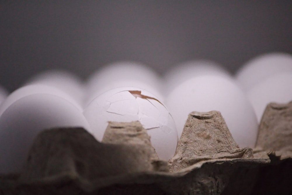 a cracked egg in a carton of eggs