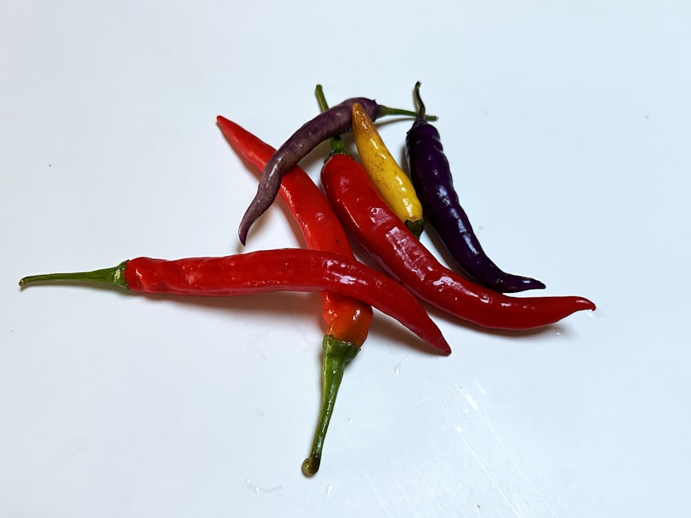a group of red, yellow, and purple peppers on a white surface