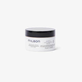 Close-up of a sleek matte pomade jar with subtle texture details on a black background.