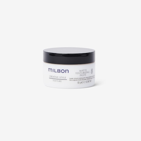 A matte texturizing paste container is centered in the image. The cylindrical container features a white body with a black lid. The brand name 'Milbon' is prominently displayed, along with product details in blue and grey text.