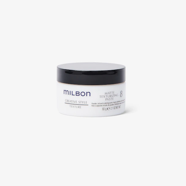 Close-up of a sleek matte pomade jar with subtle texture details on a black background.