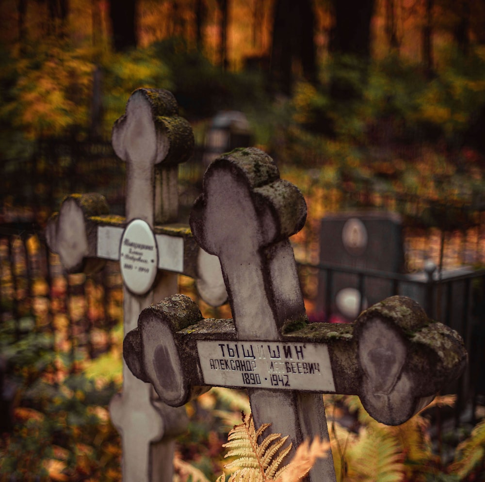 a wooden cross with a sign on it in a forest