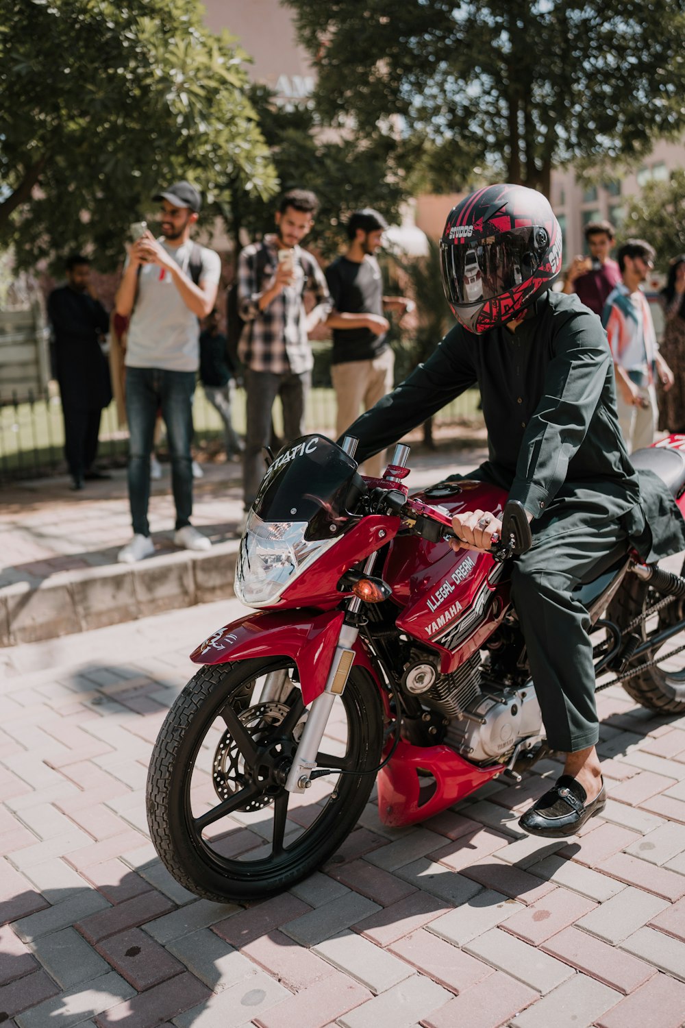 a man riding a red motorcycle down a street