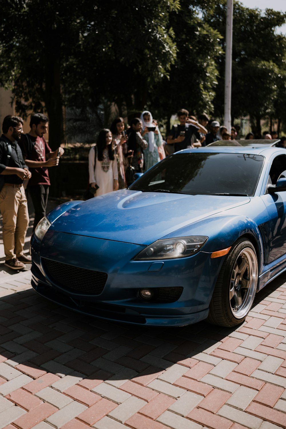 a blue sports car parked in front of a crowd of people