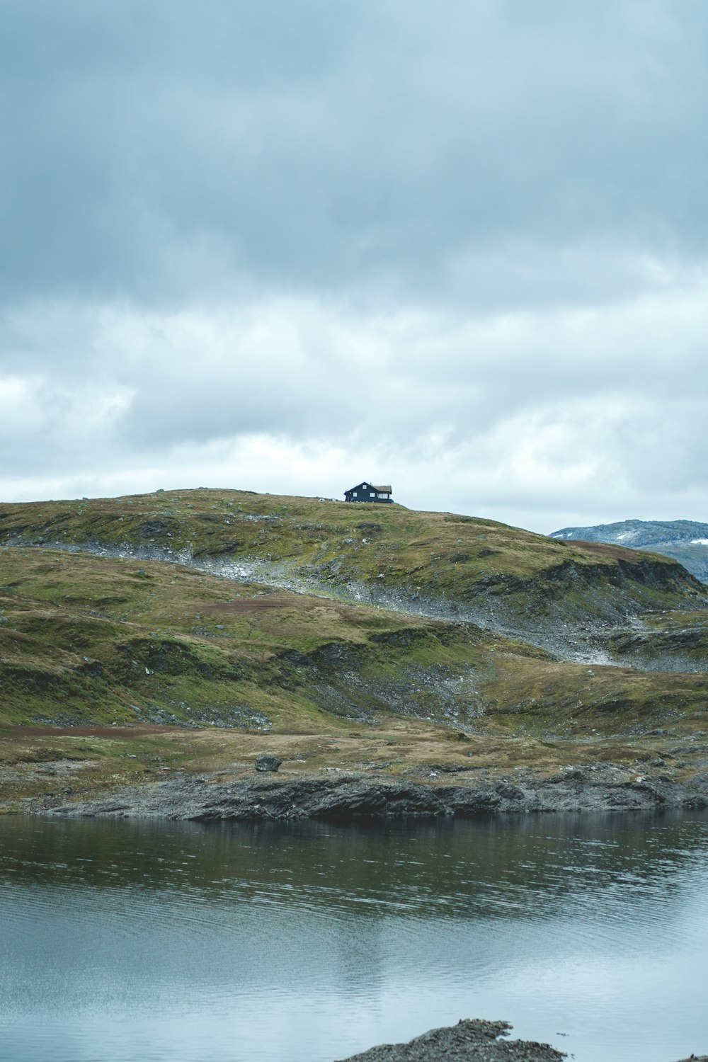 a grassy hill with a lake in the foreground