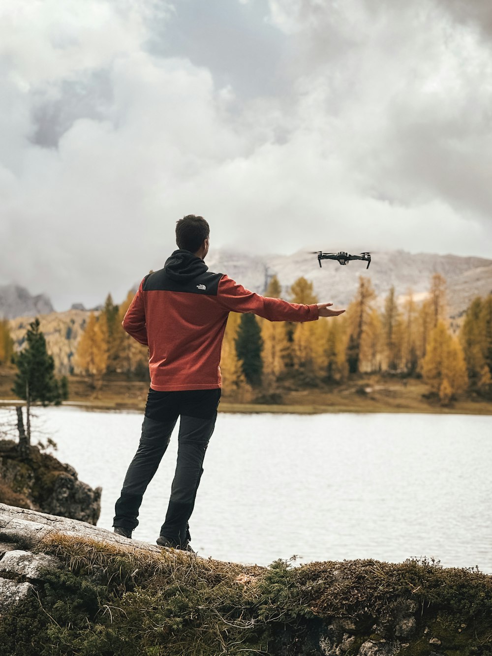 a man standing on top of a hill next to a lake