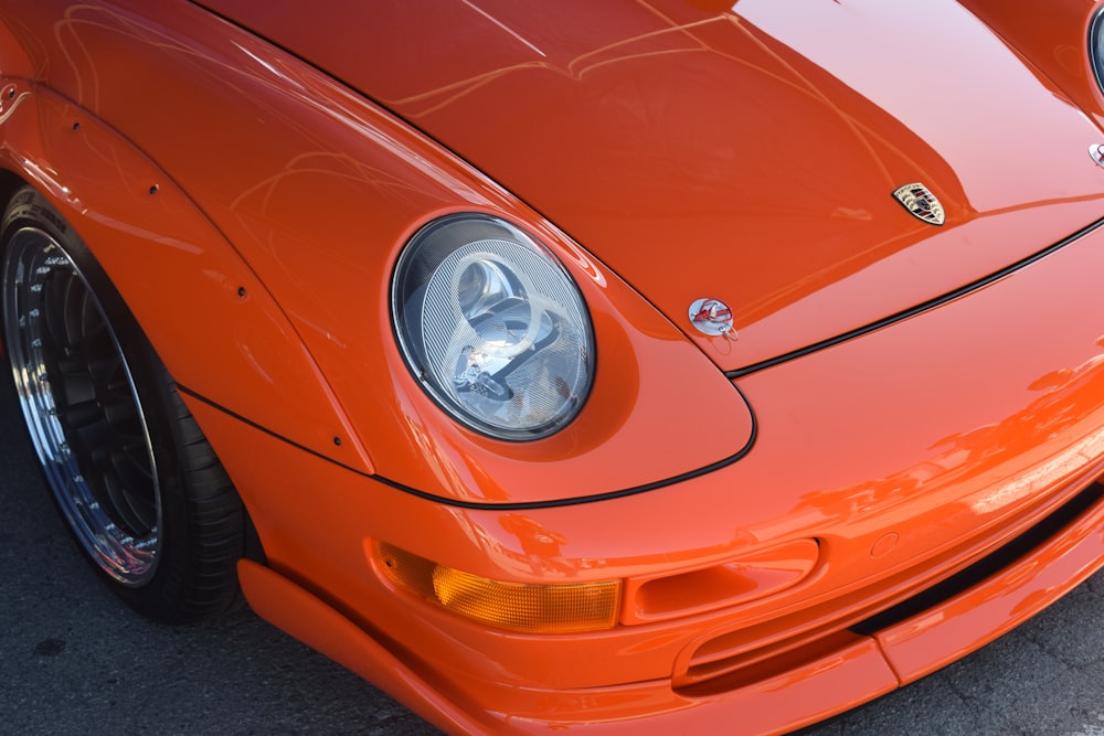 a close up of the front end of an orange sports car