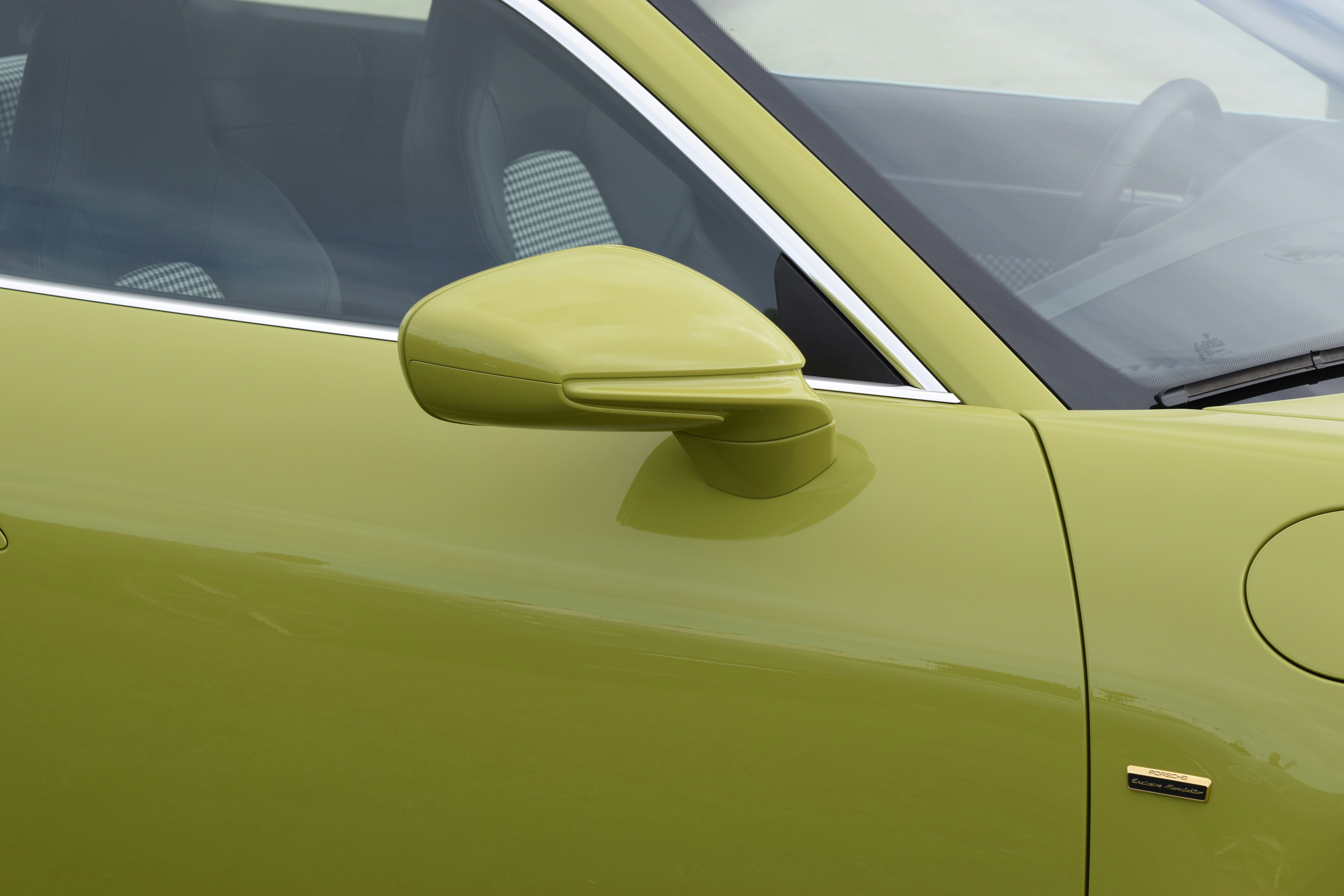 Image of a pea green passenger side door, mirror and gas cap, there is a company emblem below and to the left of the gas cap