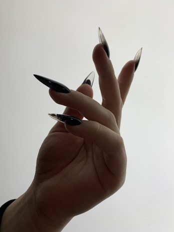 A stylish woman showing off her Necro Nails in a moody, dark-themed setting.