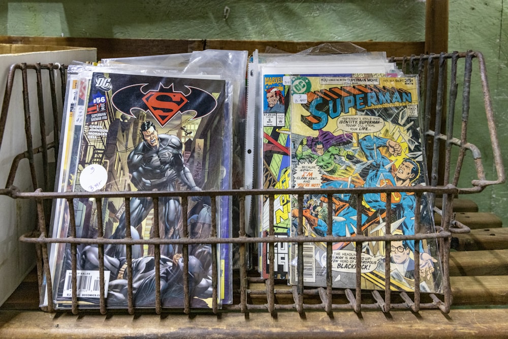 a metal basket filled with comic books on top of a table