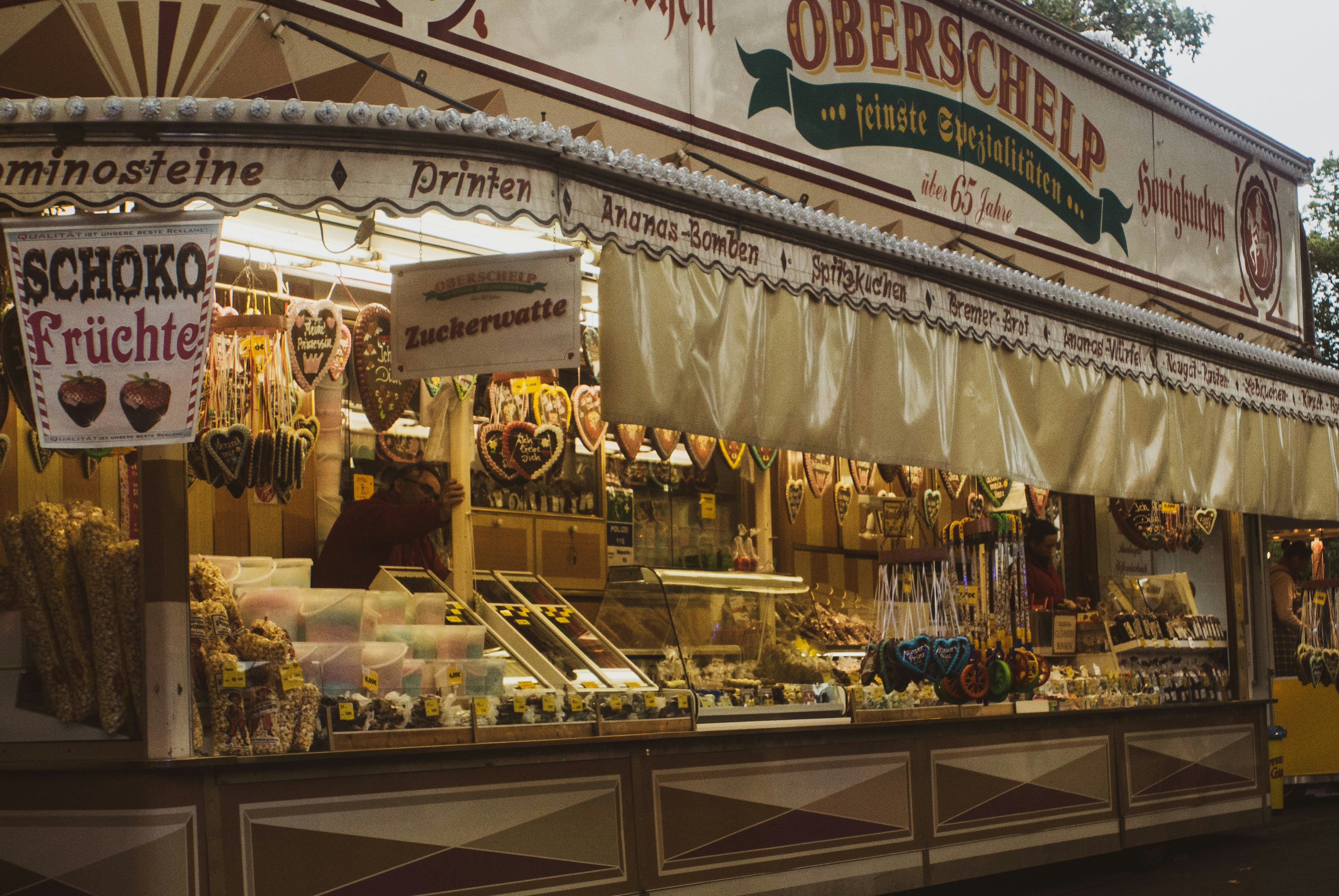 Un kiosko abierto con letreros escritos a mano y el mostrador lleno de productos