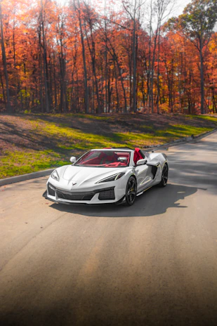 A shiny gold sports car driving along a scenic Quebec highway with autumn foliage.