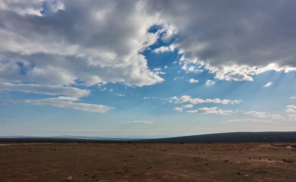 a large open field with a sky filled with clouds