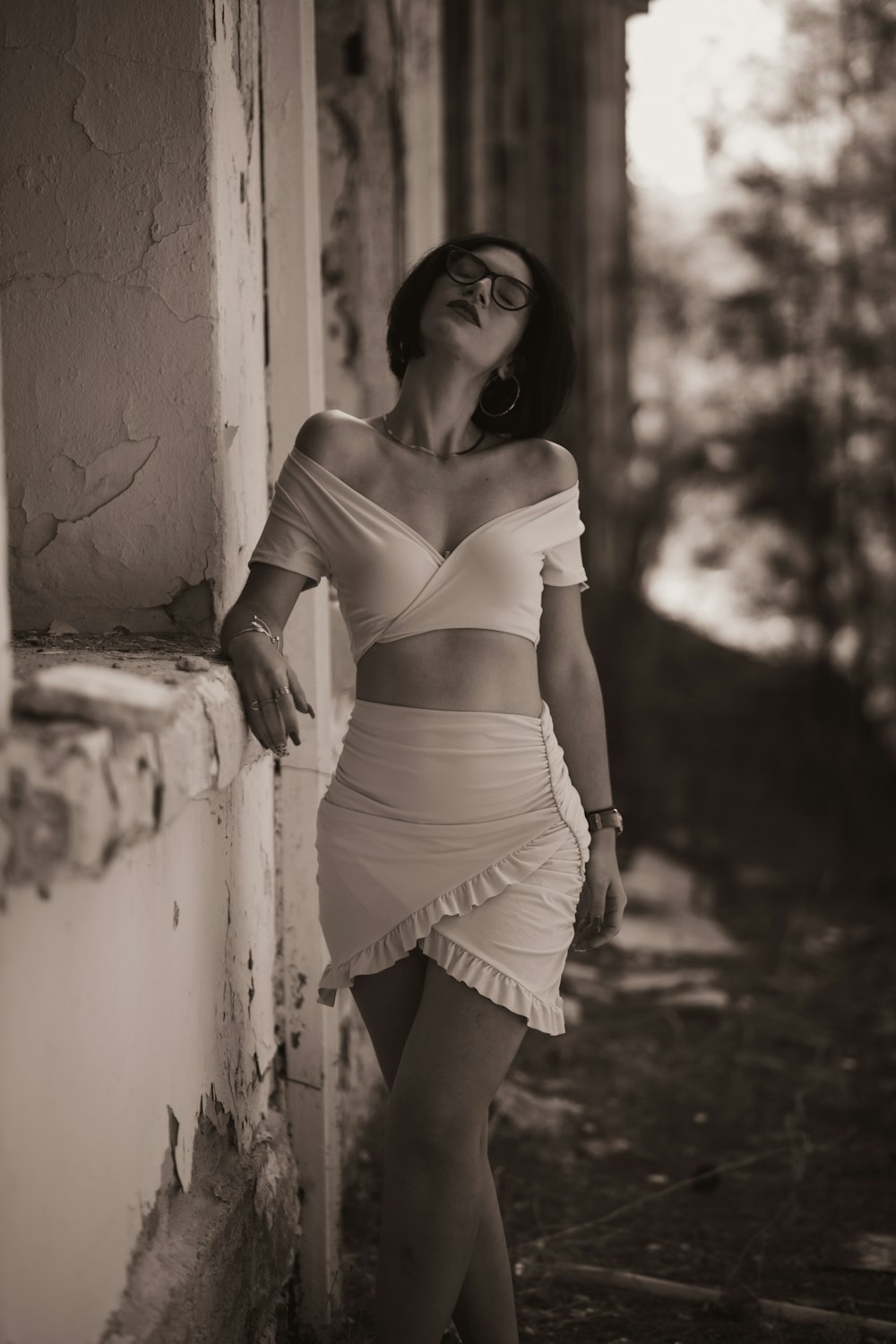 a woman leaning against a wall wearing a dress