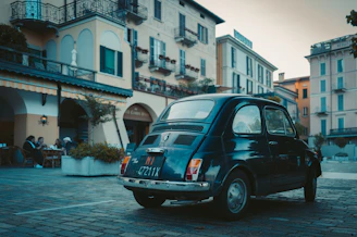 Participants enjoying a gourmet outdoor lunch beside their vintage vehicles in a charming village square.