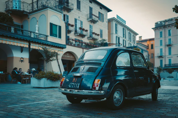 Participants enjoying a gourmet outdoor lunch beside their vintage vehicles in a charming village square.